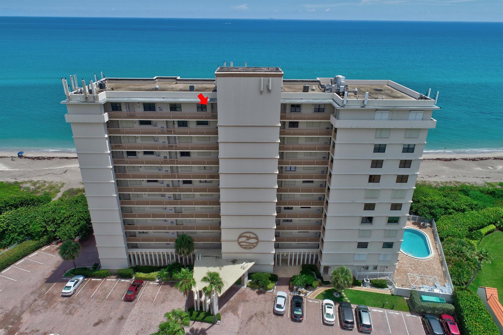 An aerial view of a high-rise beachfront condominium building with a red arrow pointing toward a balcony — 840 Ocean Drive # c, Juno Beach FL 33408, JUNO BEACH, FL