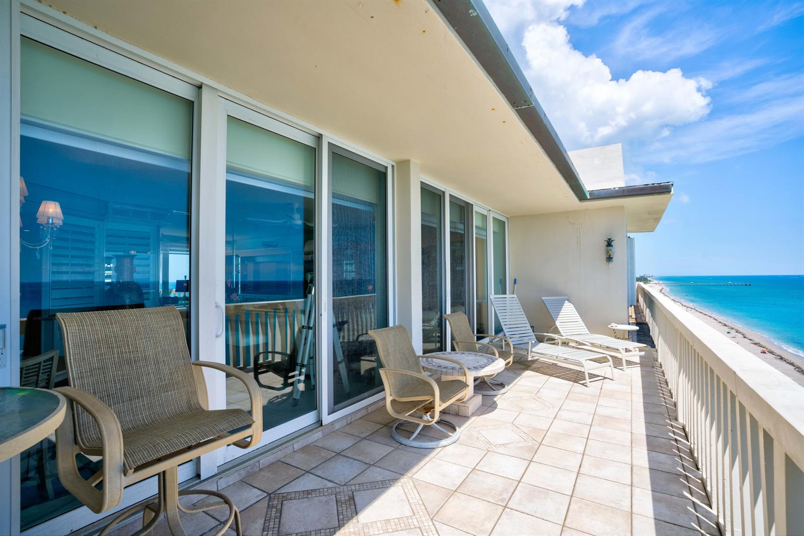 A balcony with tiled flooring, patio furniture, and sliding glass doors overlooking the ocean — 840 Ocean Drive # c, Juno Beach FL 33408, JUNO BEACH, FL