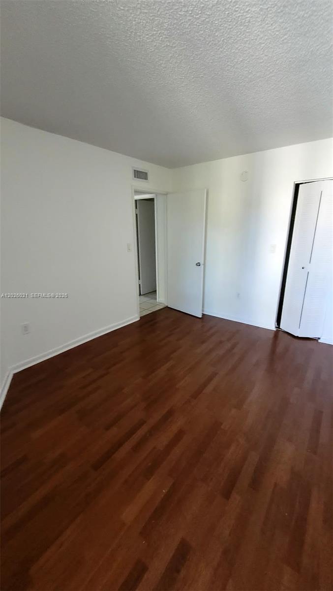 An empty room features white walls, wood-look flooring, and a white closet door — 6995 NW 186th St # E301, Hialeah FL 33015, HIALEAH, FL