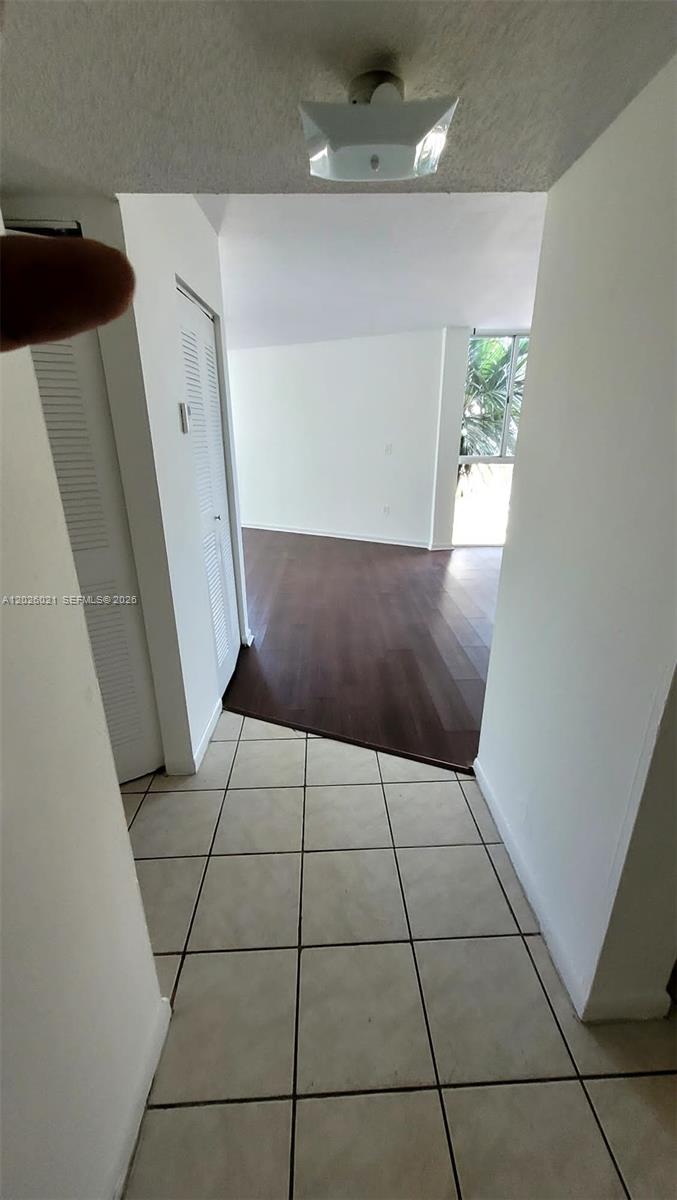 A tiled entryway leads into a living area with dark wood flooring and a window — 6995 NW 186th St # E301, Hialeah FL 33015, HIALEAH, FL