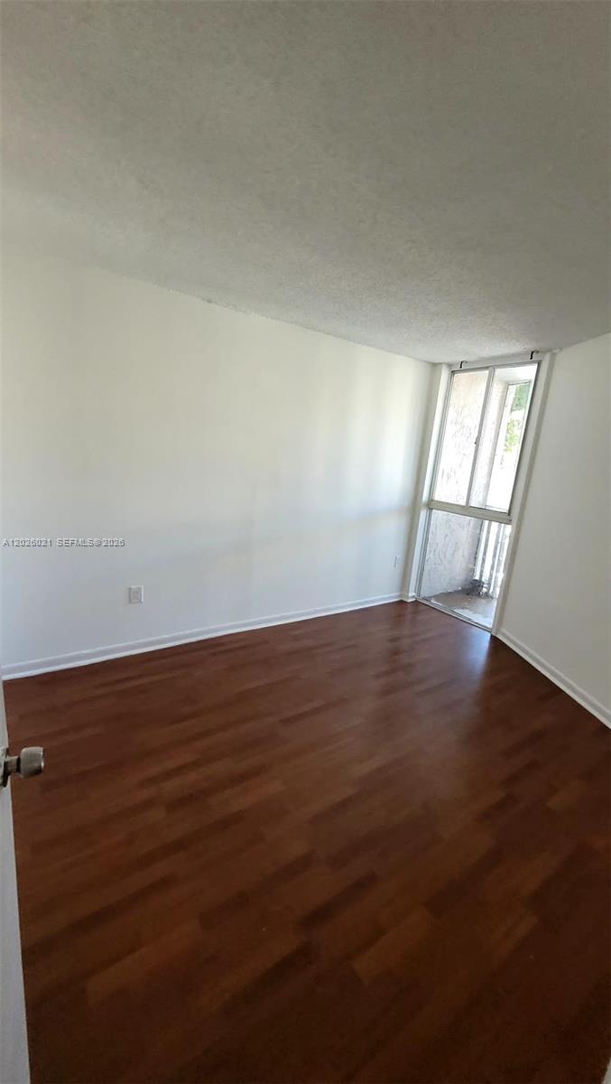 An empty room features white walls, wood-look flooring, and a glass door leading outside — 6995 NW 186th St # E301, Hialeah FL 33015, HIALEAH, FL