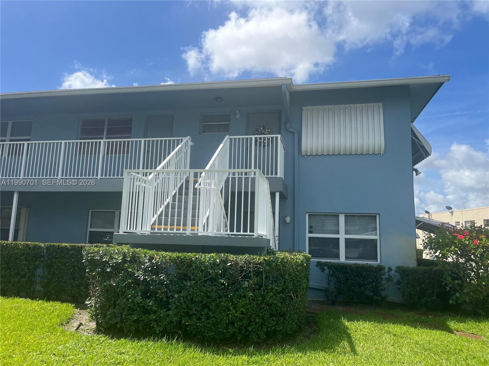 The exterior of a two-story blue apartment building features a white metal staircase and railings — 3856 S Cir Dr # 6, Hollywood FL 33021, HOLLYWOOD, FL