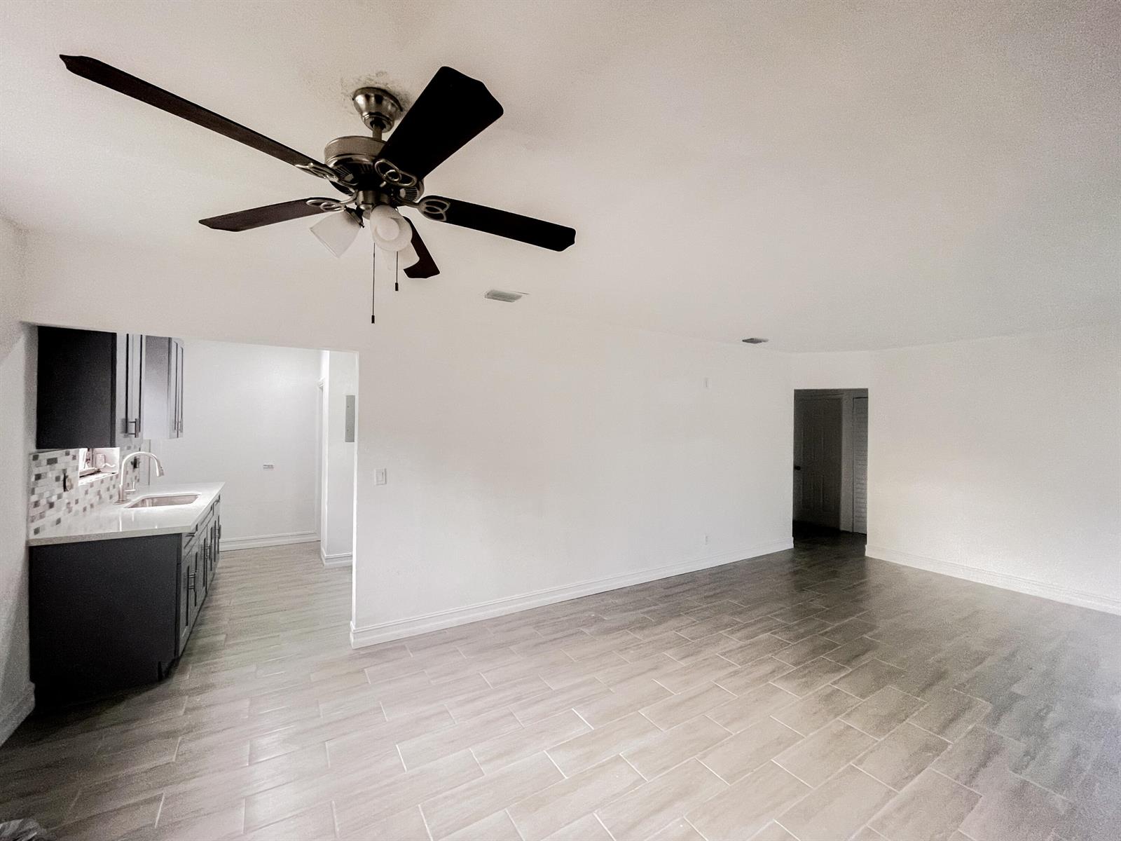 A room with light tile flooring, a ceiling fan, and an adjacent kitchen area — 841 NW 116th Terrace, Miami FL 33168, MIAMI, FL