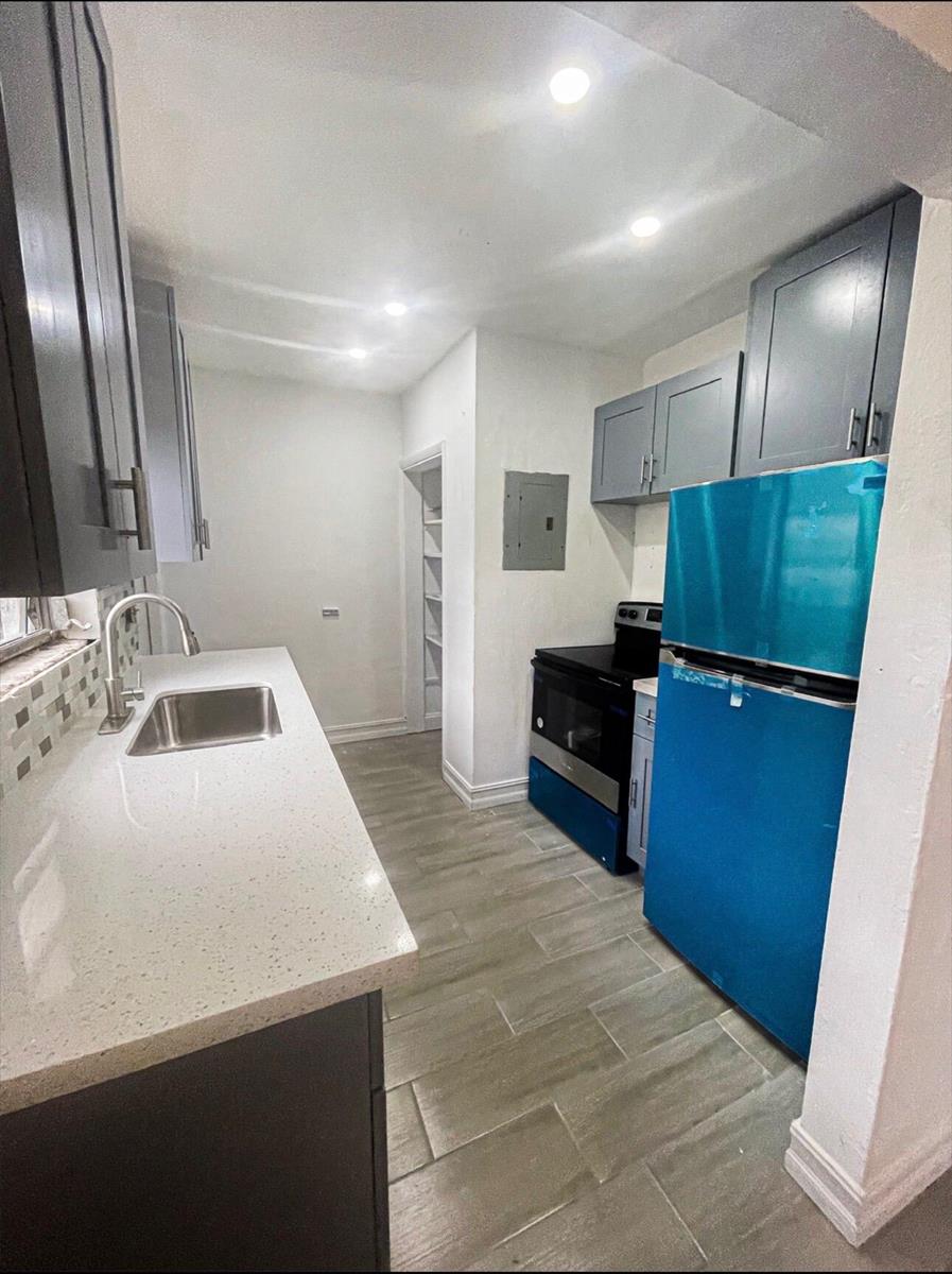 A galley kitchen features gray cabinets, white quartz countertops, stainless steel appliances, and tile flooring — 841 NW 116th Terrace, Miami FL 33168, MIAMI, FL
