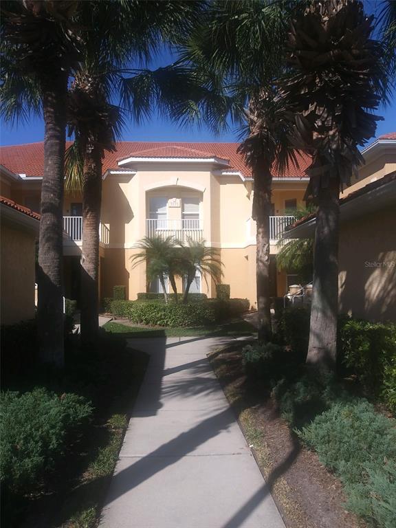 A beige building with two white garage doors and a red tiled roof — 7171 BOCA GROVE PLACE UNIT 204, LAKEWOOD RANCH, FL