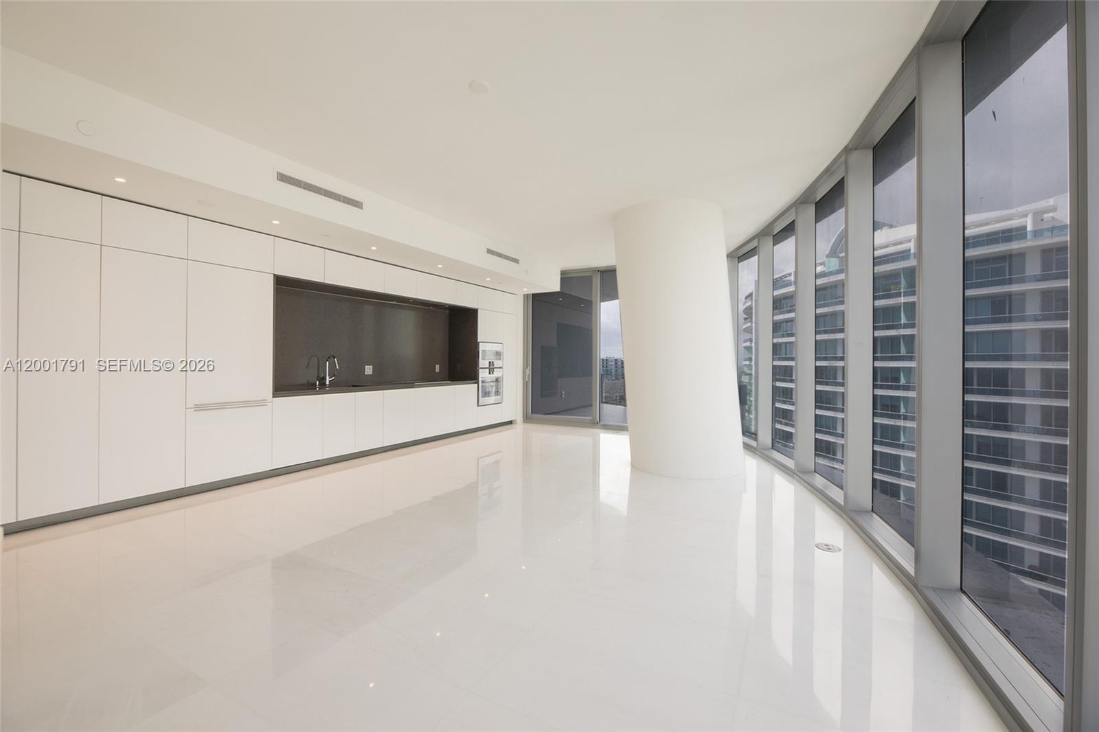A modern kitchen with white cabinetry and a large support column overlooks a city view — 300 Biscayne Boulevard Way # 4708W, Miami FL 33131, MIAMI, FL