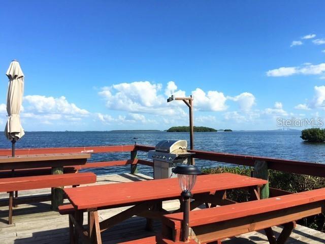 A wooden deck with picnic tables and a grill overlooks a large body of water — 1515 PINELLAS BWY S UNIT 15, TIERRA VERDE, FL