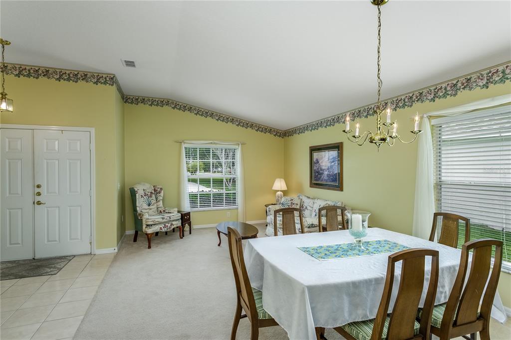 A dining room with a vaulted ceiling, light green walls, and a floral wallpaper border — 7845 GENOA LANE, LAND O LAKES, FL