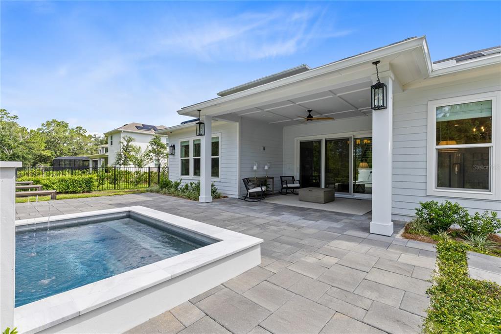 A backyard patio features a small pool, covered seating area, and light-colored siding — 3122 VANGUARD COURT, ST CLOUD, FL