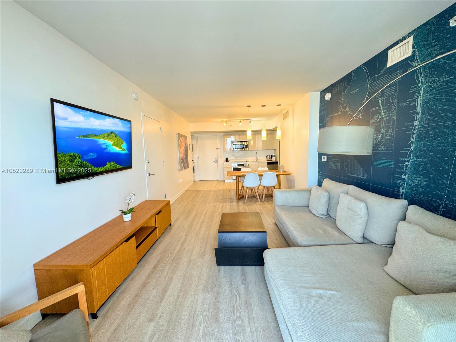 A living room features a sectional sofa, a wall-mounted television, and an open kitchen area — 2602 E Hallandale Beach # 2008A, Hallandale Beach FL 33009, HALLANDALE BEACH, FL