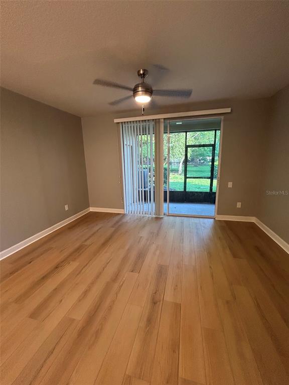 An empty room with light wood-look flooring, a ceiling fan, and sliding glass doors — 723 SHROPSHIRE LOOP, SANFORD, FL
