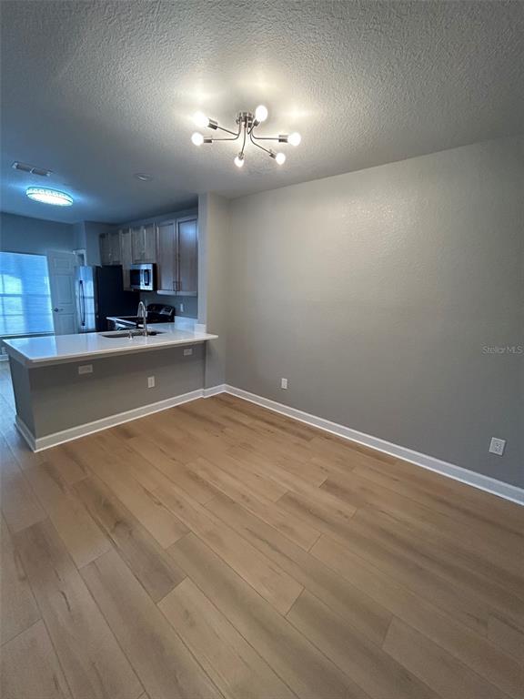 A kitchen with a breakfast bar and light wood flooring opens into a dining area — 723 SHROPSHIRE LOOP, SANFORD, FL