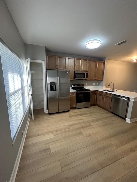 A kitchen features wood cabinets, stainless steel appliances, and light-colored wood-look flooring — 723 SHROPSHIRE LOOP, SANFORD, FL