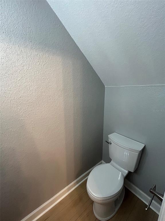 A toilet is positioned in a small room with sloped ceilings and light wood flooring — 723 SHROPSHIRE LOOP, SANFORD, FL