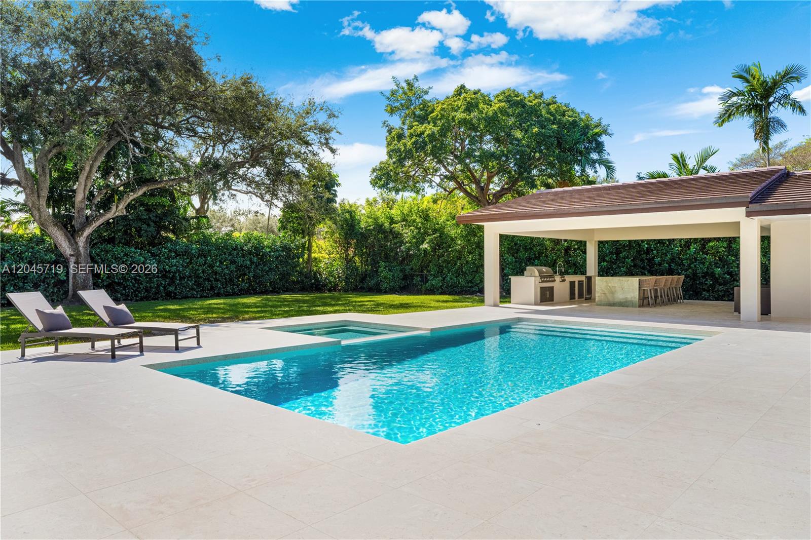 A swimming pool and spa sit on a patio next to an outdoor kitchen pavilion — 6700 SW 117th St, Pinecrest FL 33156, PINECREST, FL
