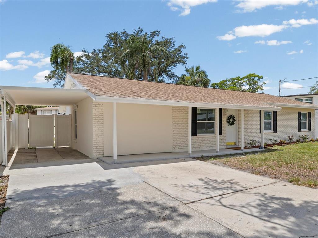 A single-story house with a beige brick exterior, a carport, and a concrete driveway — 4928 SHETLAND AVENUE, TAMPA, FL