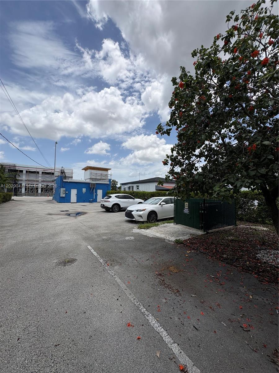 A parking lot with two cars sits in front of a blue building under a sky — 6620 W Flagler St, Miami FL 33144, MIAMI, FL