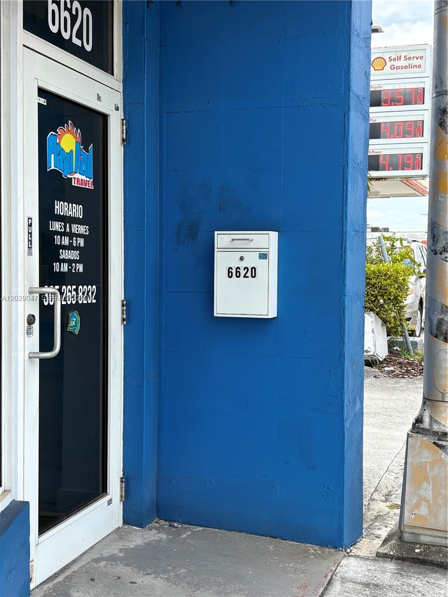 A blue exterior wall features a glass door, a white mailbox, and a gas price sign — 6620 W Flagler St, Miami FL 33144, MIAMI, FL