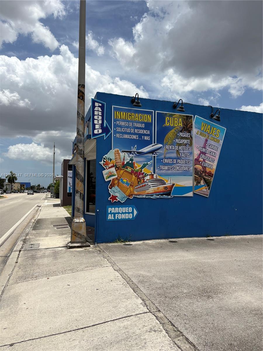 A blue commercial building exterior features signage for immigration services, travel, and parking — 6620 W Flagler St, Miami FL 33144, MIAMI, FL
