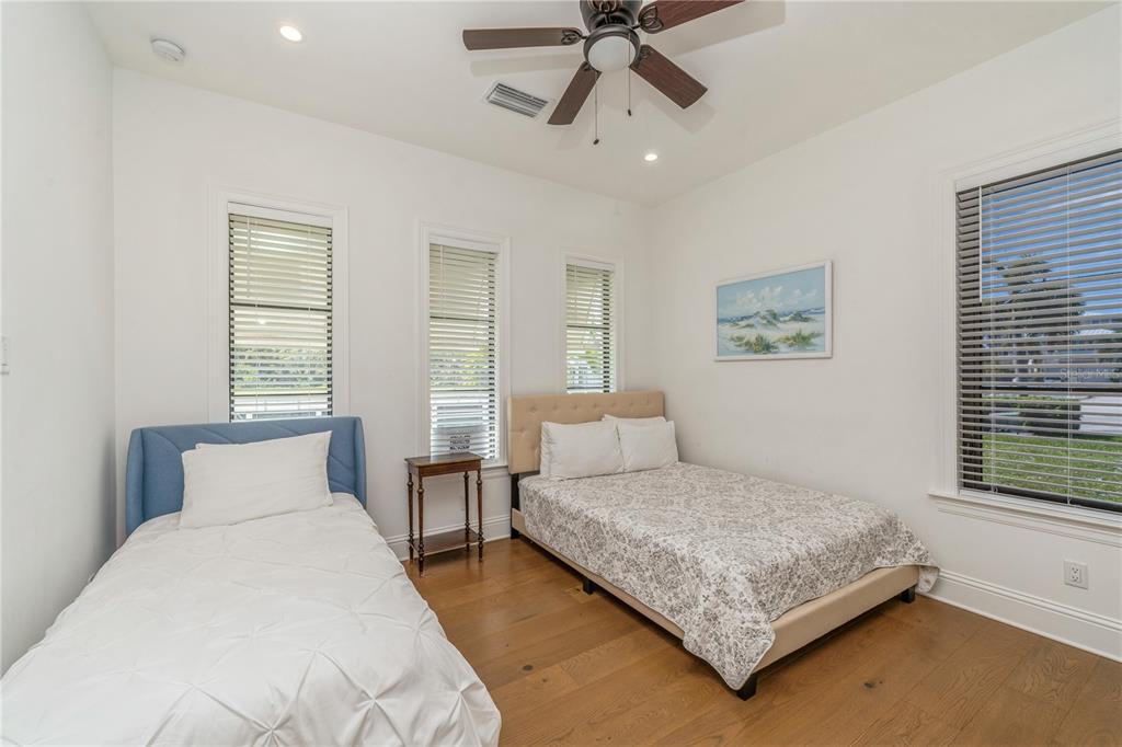 A bedroom features a twin bed, a full bed, hardwood floors, and three windows — 119 OCEAN ESTATES DRIVE, HUTCHINSON ISLAND, FL