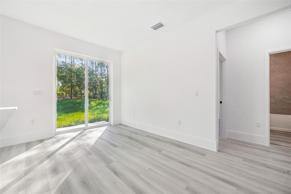 An empty room with light wood-look flooring, white walls, and a sliding glass door — 9571 N OLD MILL WAY, CITRUS SPRINGS, FL