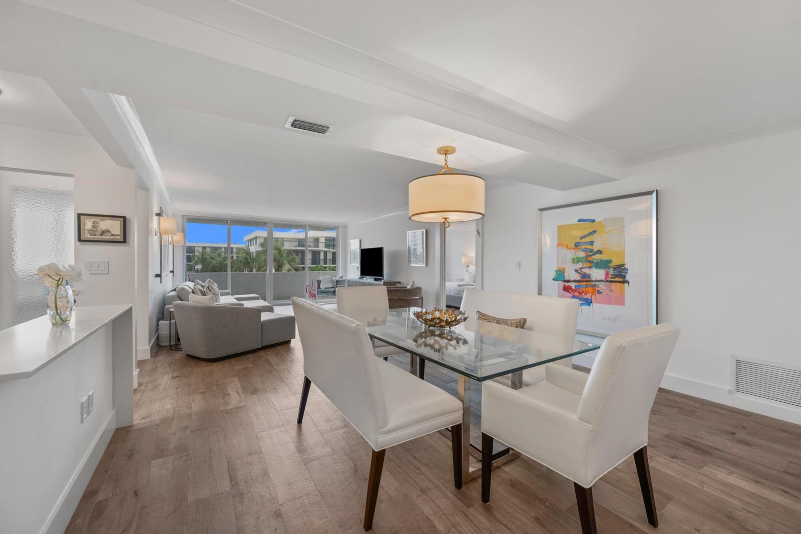 A dining area with a glass table and white chairs opens into a living room — 2773 S Ocean Boulevard # 410, Palm Beach FL 33480, PALM BEACH, FL