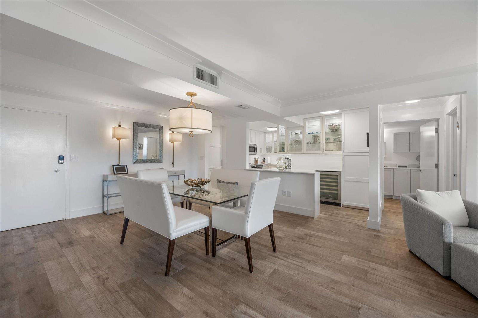 A dining area with a glass table and white chairs sits beside a modern kitchen — 2773 S Ocean Boulevard # 410, Palm Beach FL 33480, PALM BEACH, FL