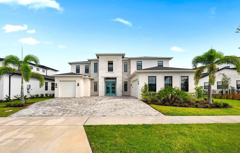 A two-story house with a stone facade, blue front door, and a paved driveway — 9453 GOLDEN LAUREL LANE, ORLANDO, FL