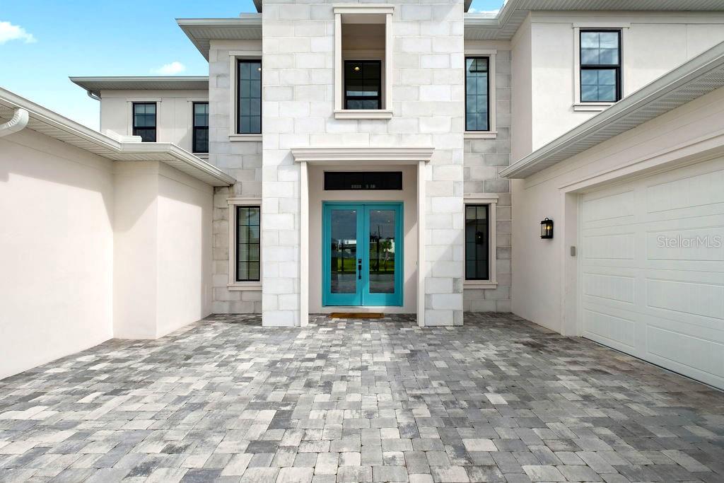 A two-story modern house with a stone facade, two garages, and a paved driveway at sunset — 9453 GOLDEN LAUREL LANE, ORLANDO, FL