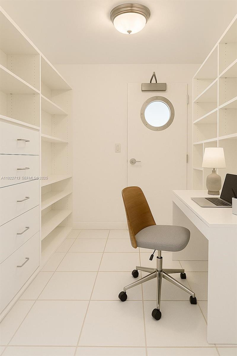 A home office features white built-in shelving, a desk, a rolling chair, and a porthole door — 5255 Collins Ave # 5D, Miami Beach FL 33140, MIAMI BEACH, FL