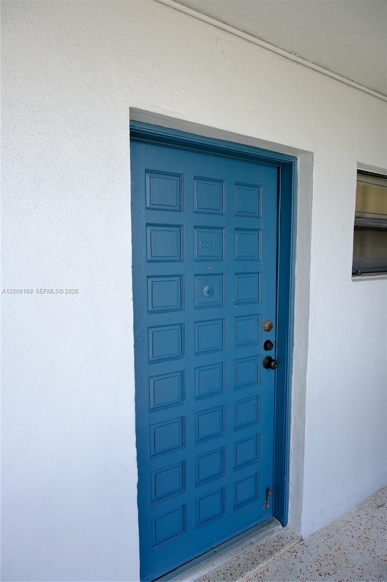 A blue paneled door is set into a white exterior wall — 650 NE 149th St # 505F, Miami FL 33161, MIAMI, FL