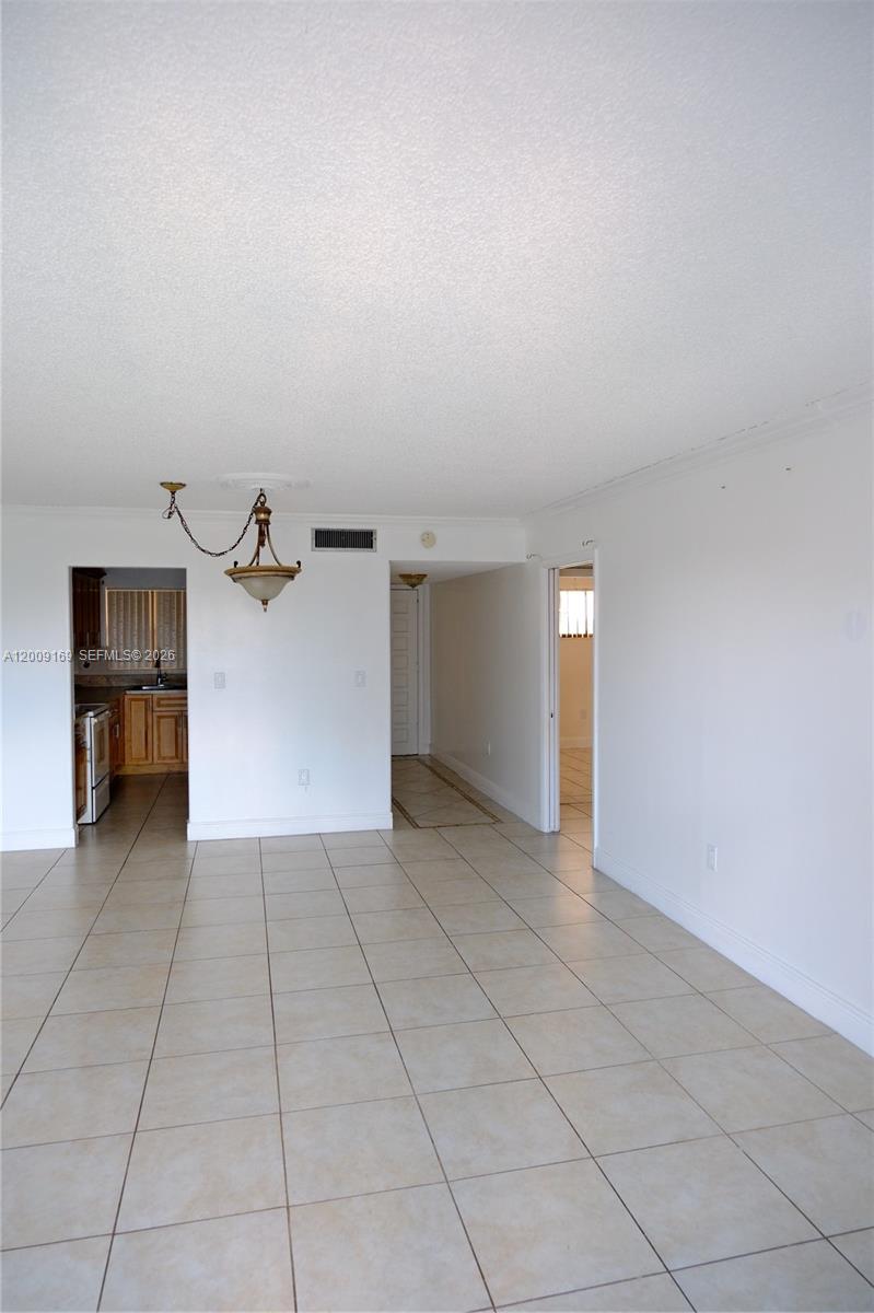 An interior view shows a tiled living area with a kitchen doorway and hallway — 650 NE 149th St # 505F, Miami FL 33161, MIAMI, FL