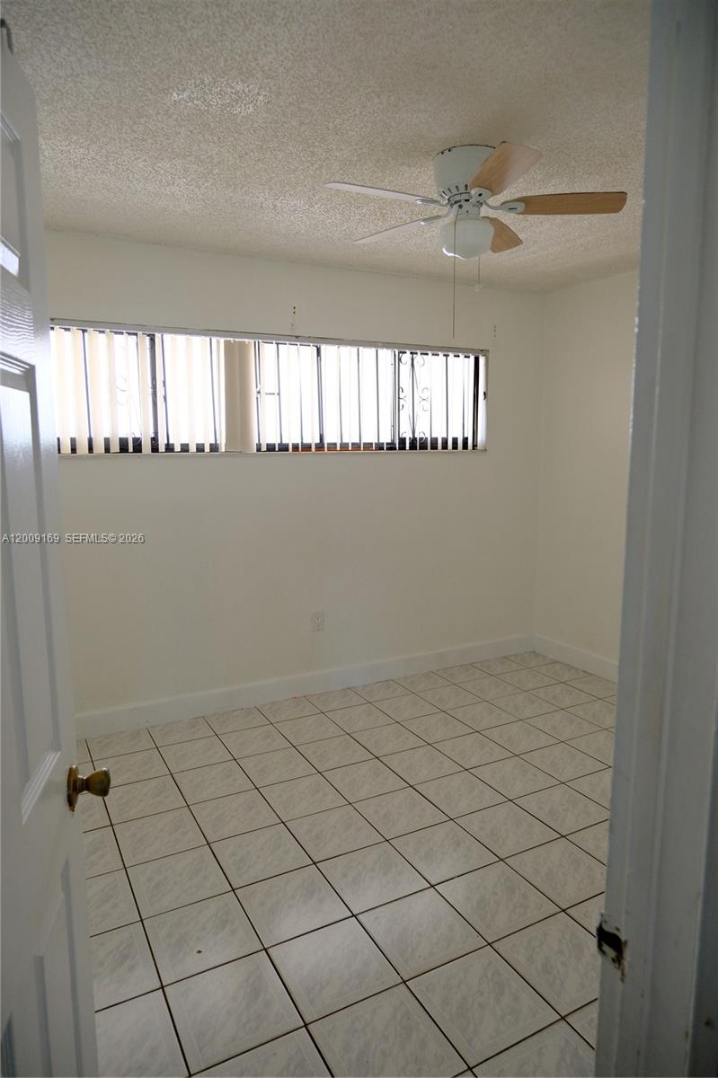 An empty room features white walls, a ceiling fan, and light-colored square floor tiles — 650 NE 149th St # 505F, Miami FL 33161, MIAMI, FL