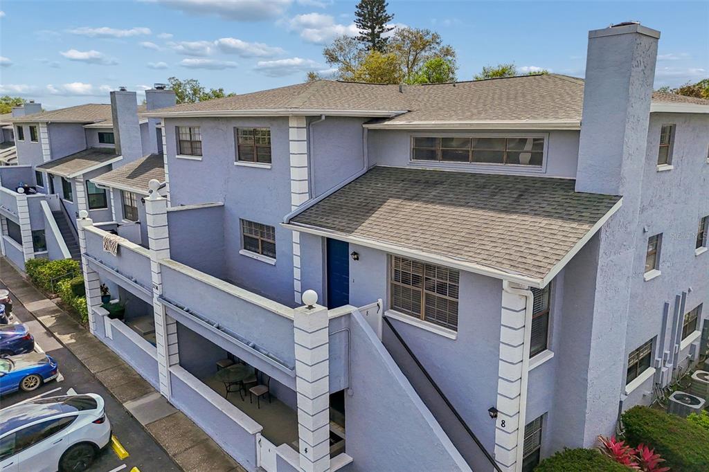 An elevated exterior view of a multi-story, light purple townhouse with a blue front door — 5756 CALAIS BOULEVARD N UNIT 8, ST PETERSBURG, FL