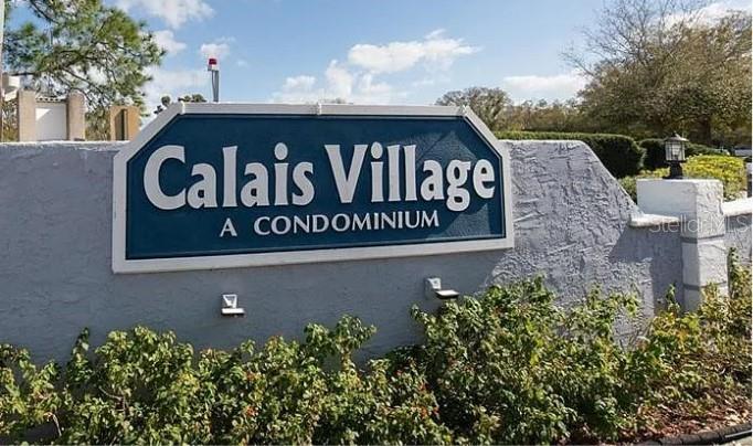 A blue and white sign for Calais Village A Condominium stands in front of landscaping — 5756 CALAIS BOULEVARD N UNIT 8, ST PETERSBURG, FL