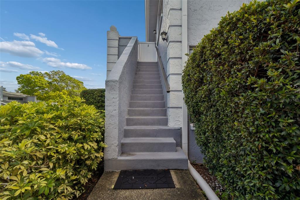 An outdoor concrete staircase leads to a white gate at the entrance of a building — 5756 CALAIS BOULEVARD N UNIT 8, ST PETERSBURG, FL