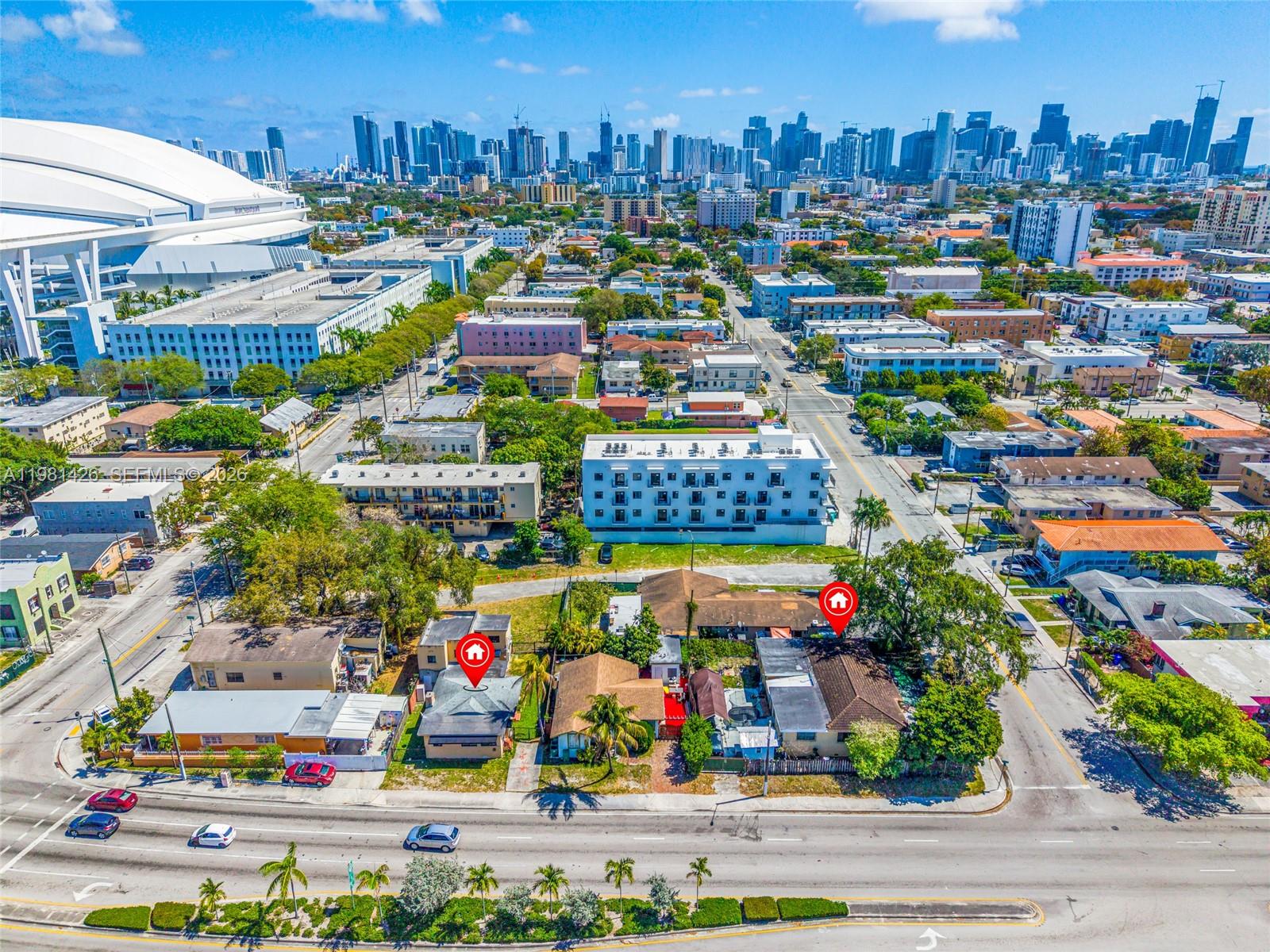 An aerial view shows two adjacent residential properties marked with red house icons near a stadium — 1675 NW 2nd St, Miami FL 33125, MIAMI, FL