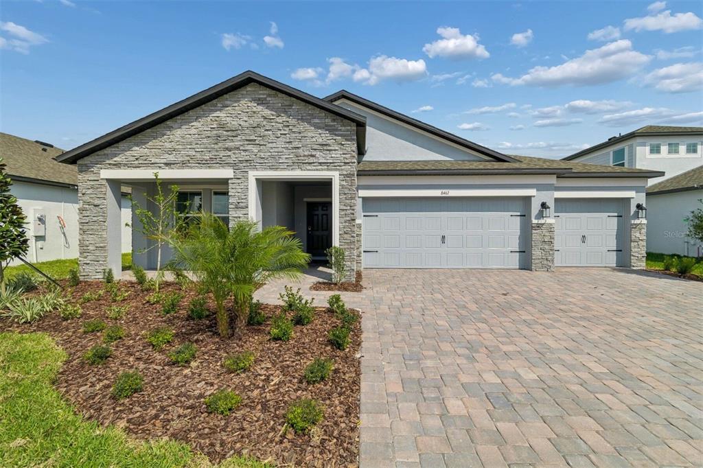 A single-story house with a stone facade, a three-car garage, and a paved driveway — 8461 FOX DEN COVE, LAKELAND, FL