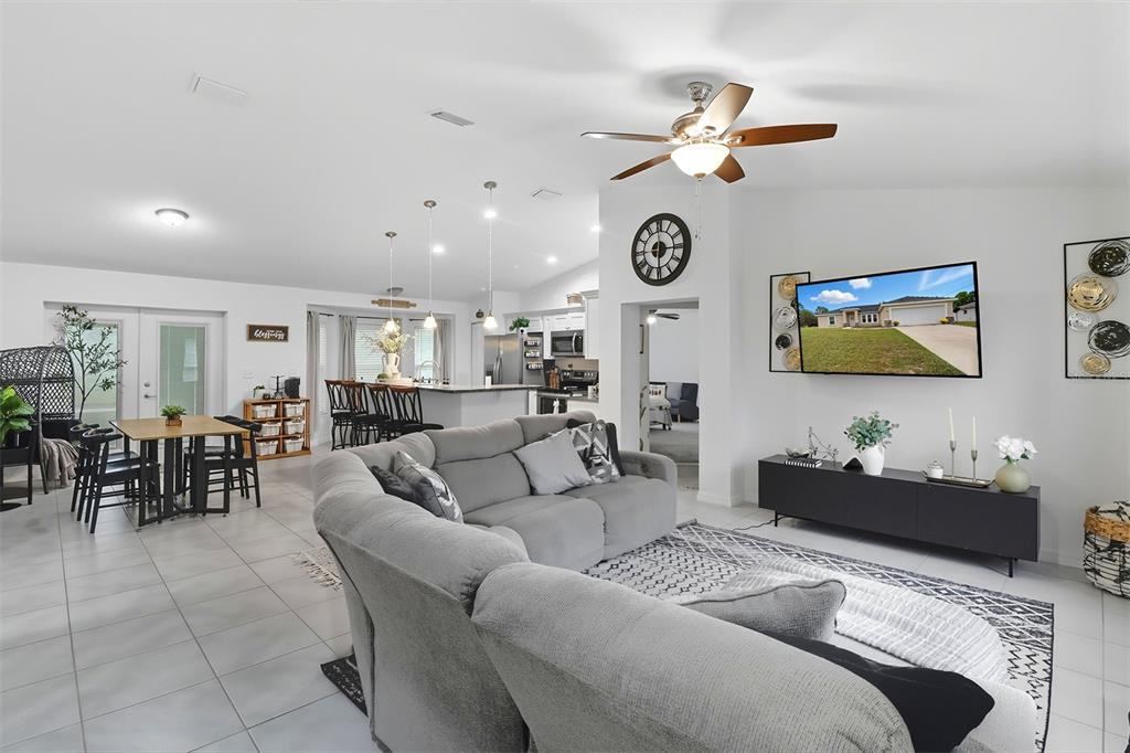 An open-concept living room features a grey sectional sofa, dining area, and kitchen with island — 6651 SW 151ST LOOP, OCALA, FL