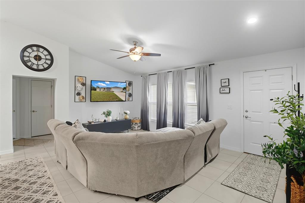A living room features a large sectional sofa, a wall-mounted television, and ombre curtains — 6651 SW 151ST LOOP, OCALA, FL