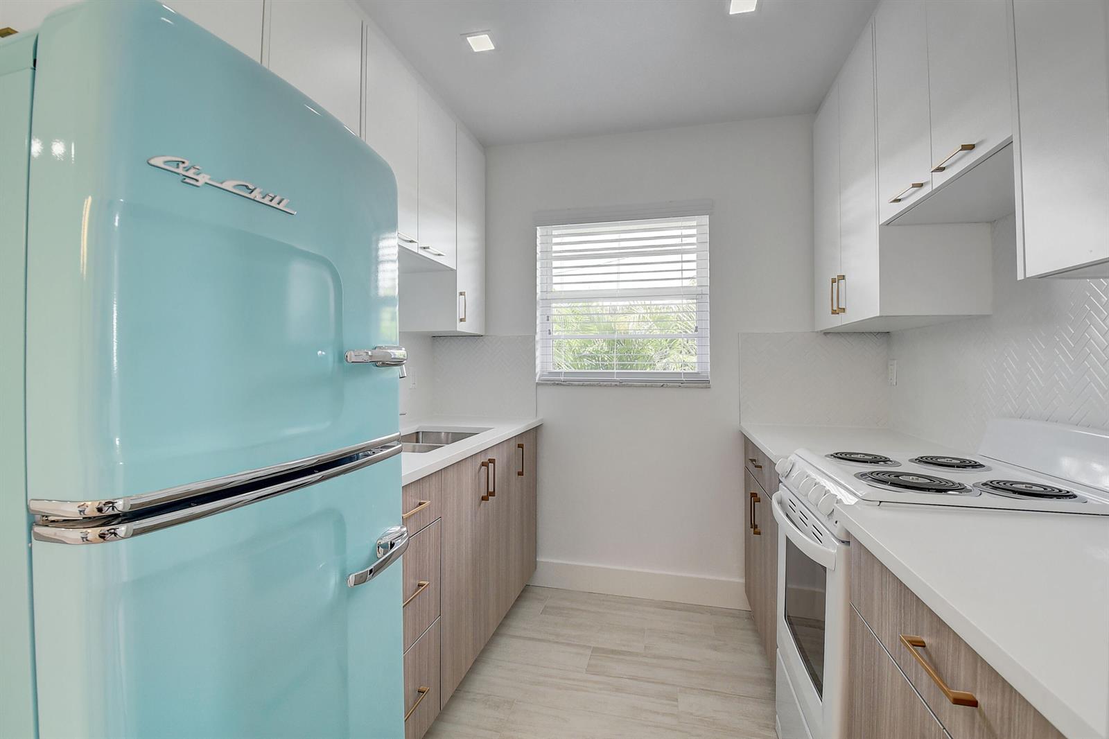 A galley kitchen features a light blue retro refrigerator, wood-tone cabinets, and white countertops — 502 N H Street # 4, FL 33460, FL