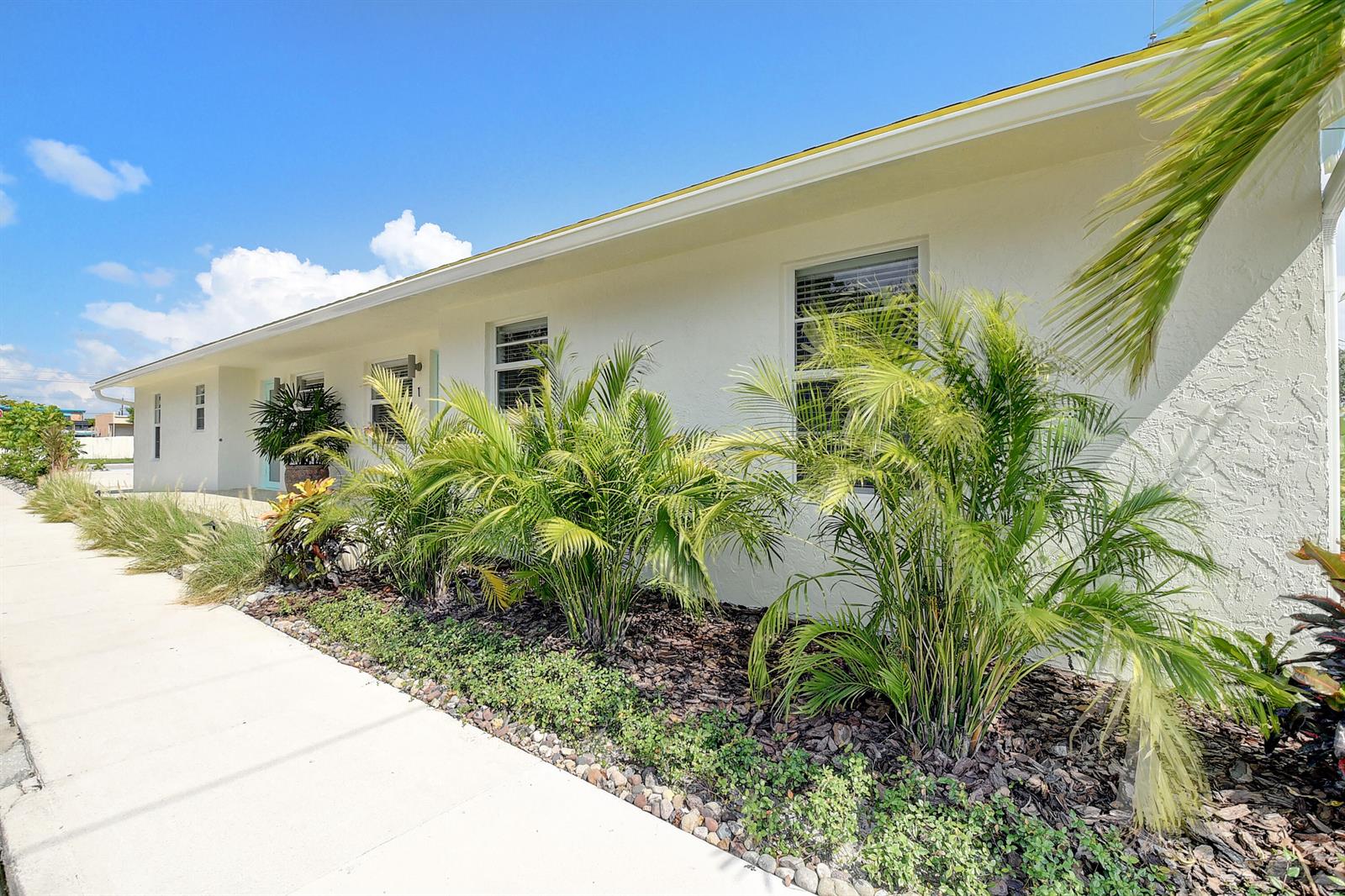 A white house exterior with palm trees and landscaping along a concrete sidewalk — 502 N H Street # 4, FL 33460, FL