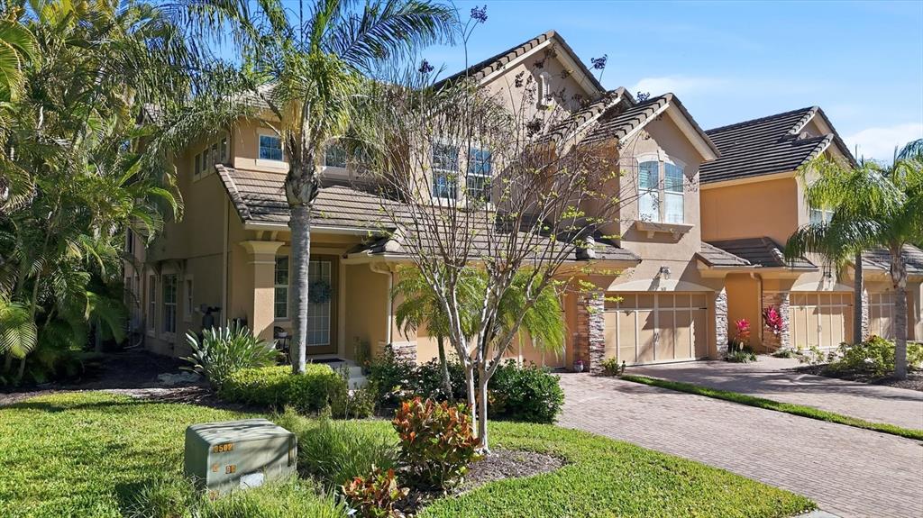 A two-story tan stucco townhouse with a tile roof and a paved driveway — 5427 NAPA DRIVE, SARASOTA, FL
