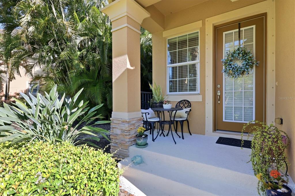 A covered front porch features a small bistro table, two chairs, and a glass-paneled door — 5427 NAPA DRIVE, SARASOTA, FL