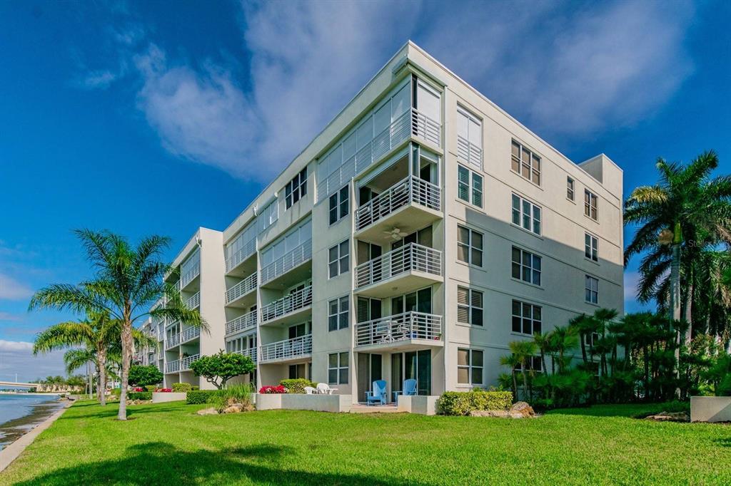 A multi-story apartment building with balconies stands next to a grassy lawn and a canal — 6085 BAHIA DEL MAR CIRCLE UNIT 468, ST PETERSBURG, FL