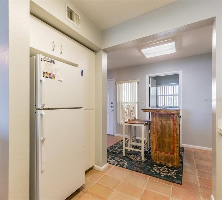 A kitchen features a white refrigerator, tiled floors, and a small wooden breakfast bar — 6085 BAHIA DEL MAR CIRCLE UNIT 468, ST PETERSBURG, FL