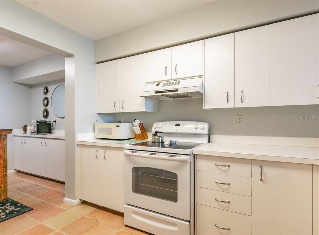 A kitchen features white cabinets, white appliances, and light-colored countertops with tile flooring — 6085 BAHIA DEL MAR CIRCLE UNIT 468, ST PETERSBURG, FL
