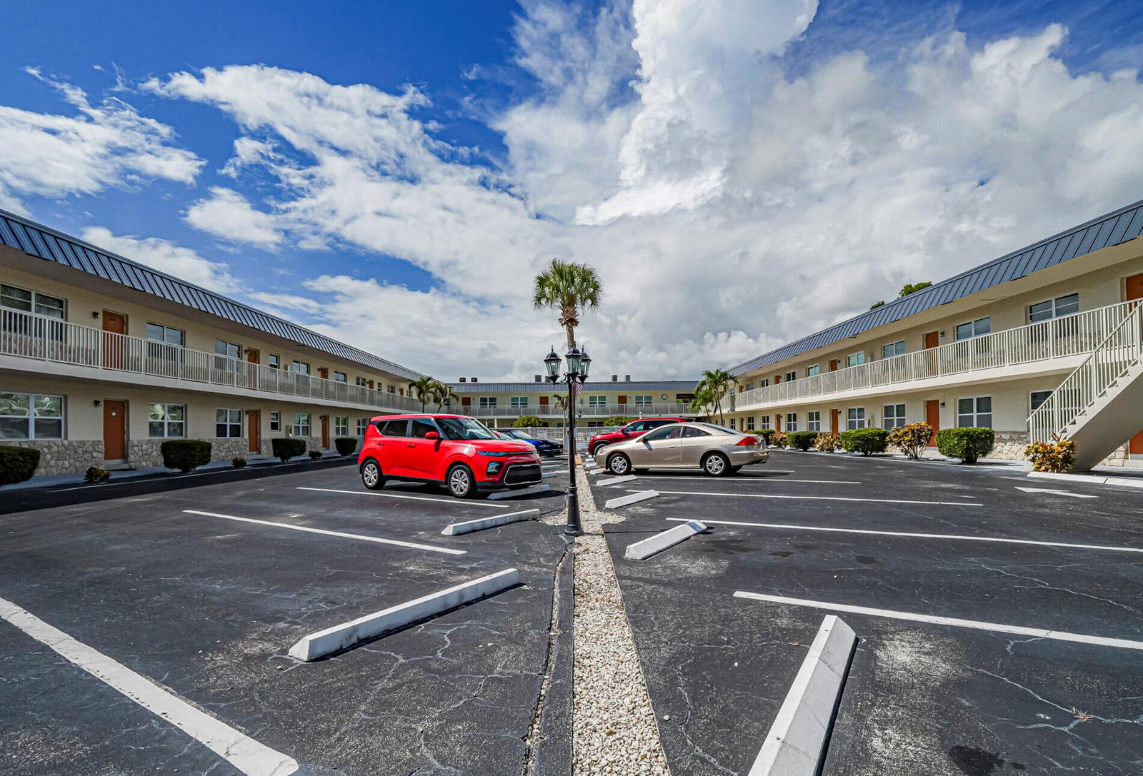 An exterior view of a two-story motel with a parking lot and two cars — 923 22nd Place # 219, Vero Beach FL 32960, VERO BEACH, FL
