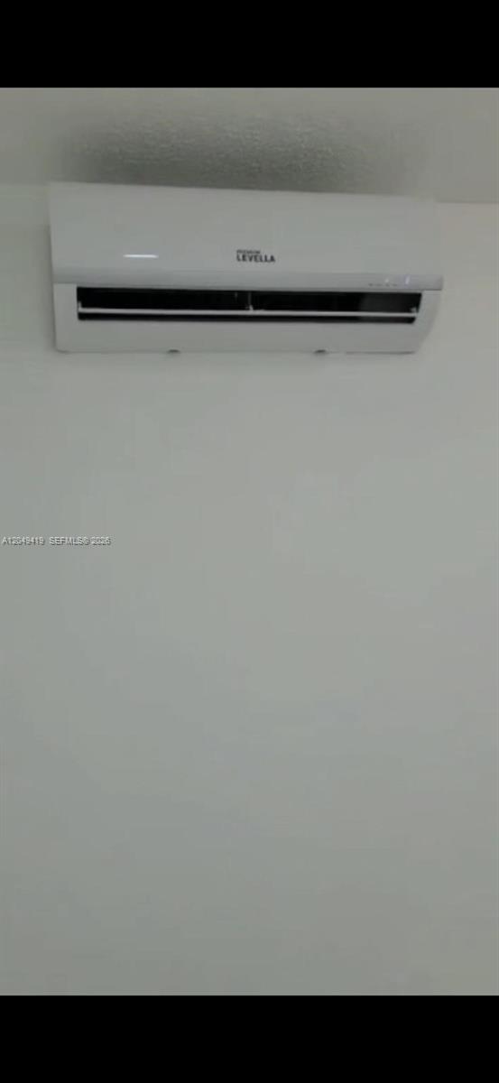 A white wall-mounted ductless mini-split air conditioning unit is installed on a plain white wall — MIAMI, FL