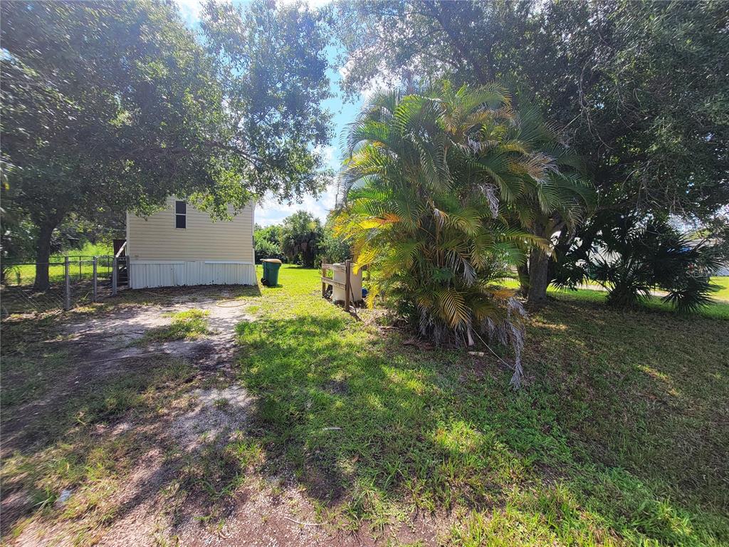 A side view of a light-colored mobile home with a palm tree in the yard — 5504 WILSON DRIVE, PUNTA GORDA, FL